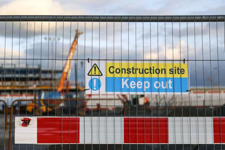 A crane and a construction site being secured behind safety barriers