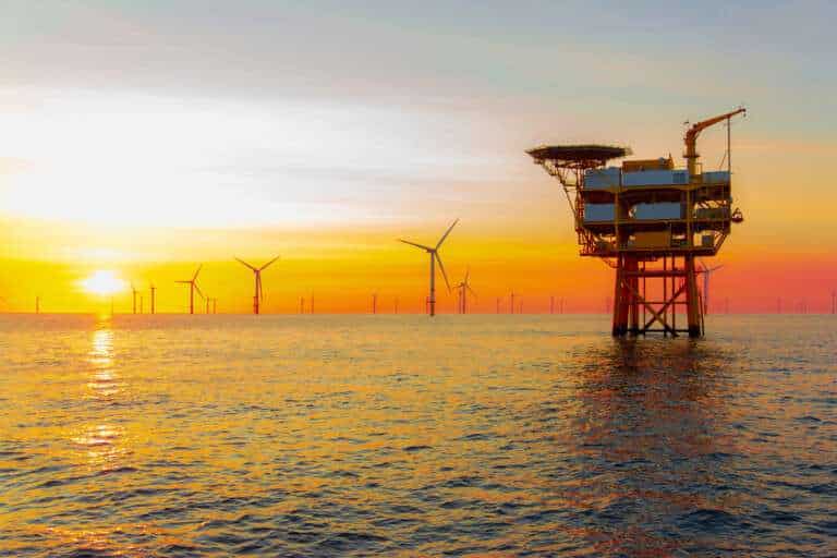 Offshore wind farm and the turbines spinning with the sunset in the background